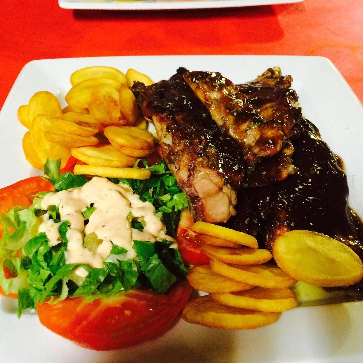 Carne a la parrilla servida con patatas y ensalada en O Meraklis